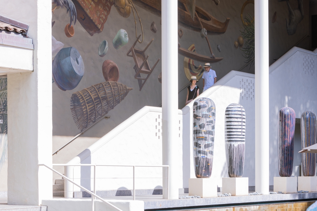 A couple wearing straw hats walking down the decorative stairs of the Honolulu Museum of Art (HoMA) in Honolulu, HI.